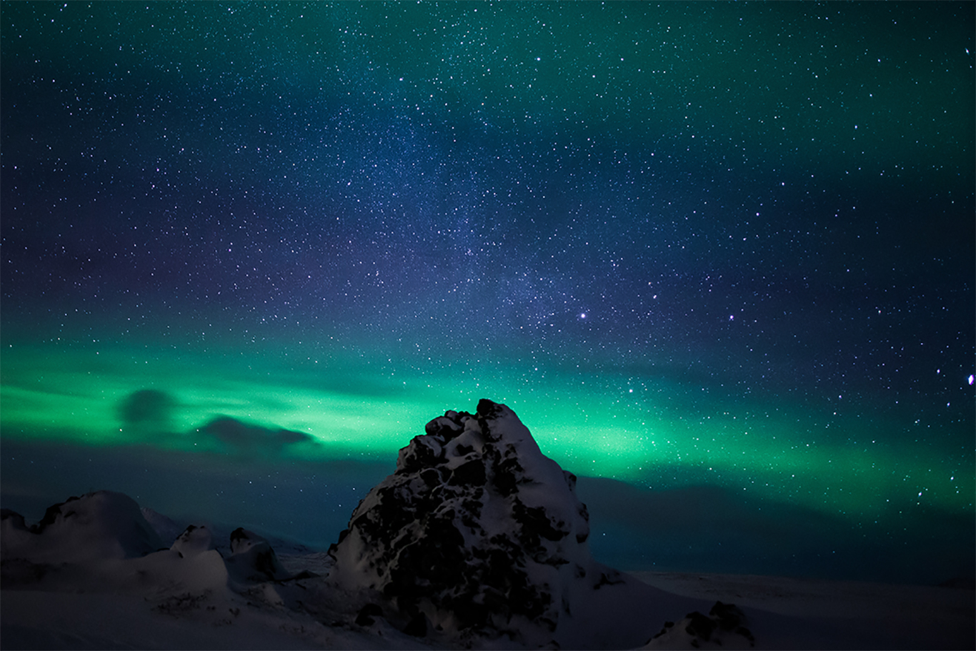 Green northern lights glowing across a dark night sky above an Arctic landscape